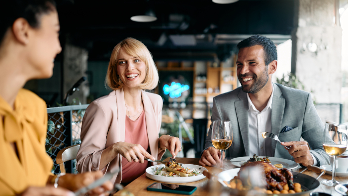 Happy business colleagues talking while eating lunch in a restaurant.