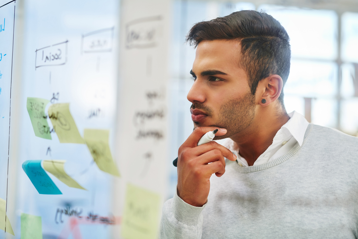 Shot of a young businessman brainstorming on a glass wall in an office